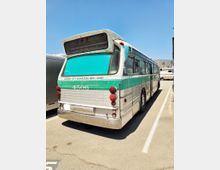 Ein vintage Linienbus mit der Aufschrift "Culver City Municipal Bus Lines" und der Nummer 4506, geparkt auf einem asphaltierten Parkplatz bei Tageslicht. Der Bus ist türkis und silberfarben, mit runden Rücklichtern und einem großen Lüftungsgitter am Heck.