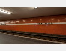 U-Bahn-Station mit rot gekachelter Wand, darauf der Schriftzug „Yorckstraße“ in schwarzen Buchstaben auf weißem Hintergrund. Im Vordergrund sind die Gleise und der Bahnsteig erkennbar, die Decke ist mit einfachen Leuchtstoffröhren beleuchtet.