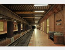 U-Bahn-Station mit Ziegelwänden, rechteckigen Säulen und einem Gleis rechts neben einem breiten, gefliesten Bahnsteig. An der Wand ist der Stationsname "Zitadelle" mit einem Richtungsschild zum Ausgang angebracht; die Beleuchtung erfolgt durch lange Leuchtstofflampen an der Decke.