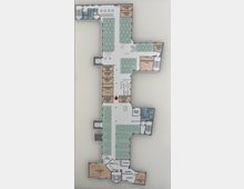 Gebäudeflächenplan eines Büro- oder Veranstaltungsraums mit markierten Bereichen wie Besprechungsräumen, Arbeitsplätzen, Teeküchen, einer Rezeption und Themenräumen wie "Autokino" und "Carrera Club". Die verschiedenen Zonen sind in unterschiedlichen Farben hervorgehoben, und Pfeile zeigen Zugänge sowie Raumaufteilungen.