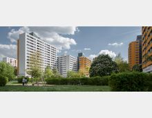 Wohngebiet mit hohen, mehrstöckigen Wohnblocks in Weiß und Orange, umgeben von Grünflächen mit Bäumen und Sträuchern. Im Vordergrund befindet sich ein kleiner Spielplatz mit einer Rutsche und ein paar Passanten.