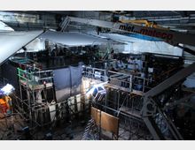 Filmstudio mit komplexer Kulisse: Eine Halle mit Gerüsten, Scheinwerfern, Kamerakränen und einem künstlichen Wasserbecken, umgeben von technischen Geräten und reflektierenden Leinwänden.