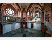 Innenraum einer umgenutzten Backsteinkirche mit hohen Spitzbögen, einem runden Rosettenfenster und Backsteinarkaden. Der Raum wurde modern gestaltet, mit einem offenen zweistöckigen Aufbau, einer großen Orgel, Glaswänden und geschwungenen Sitzreihen.