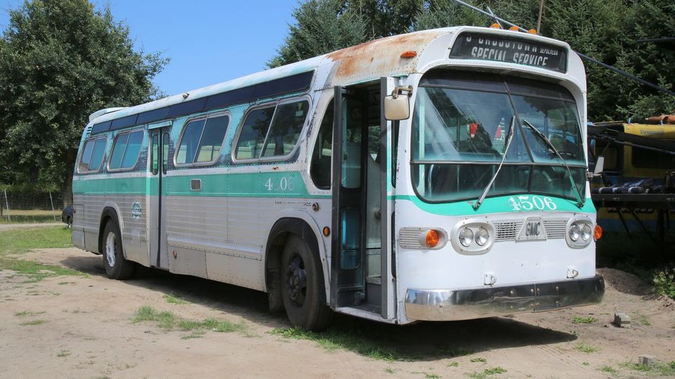 Ein alter Bus mit grün-weißer Lackierung, der am Rand eines offenen Geländes steht. Der Bus hat runde Scheinwerfer, große Seitenfenster und trägt die Nummer "4506" sowie die Aufschrift "Special Service".