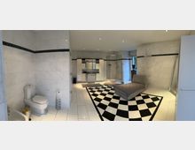 Großes Badezimmer mit weißen, marmorierten Wand- und Bodenfliesen sowie einer schwarz-weißen Schachbrett-Musterung in der Mitte des Raumes. Zu sehen sind eine Toilette, eine Dusche, ein Waschtisch mit Spiegeln, ein Heizkörper sowie eine graue Liege; der Raum ist hell beleuchtet und verfügt über ein großes Fenster.