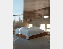 Modernes Schlafzimmer mit einem Bett aus Holz und weißer Bettwäsche, daneben eine Stehlampe. Im Hintergrund sind ein großes Fenster mit Blick auf Bäume und Gebäude sowie ein rechteckiger Wandspiegel sichtbar.