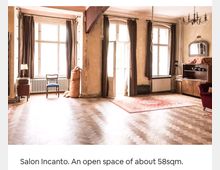 Ein großzügiger, lichtdurchfluteter Raum mit hellen Holzböden, großen Fenstern mit braunen Vorhängen, einem roten Teppich und antikem Holzmobiliar. Im Raum stehen unter anderem ein Sessel, ein Stuhl und ein Schrank, die Wände sind dezent abgenutzt und verleihen dem Raum ein rustikales Ambiente.