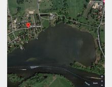 Luftaufnahme einer Flusslandschaft entlang der Havel mit umliegenden Siedlungen, Feldern und Grünflächen. Der Fluss bildet eine breite Wasserfläche, umgeben von kleinen Straßen und verstreut liegenden Gebäuden.