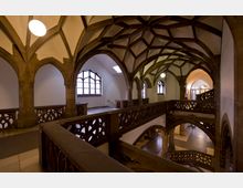 Gotischer Innenraum mit hohen Spitzbögen, einem kunstvollen Gewölbe und dekorativen Holzgeländern. Große Fenster mit Buntglas und diffuses Licht betonen die historische Architektur.