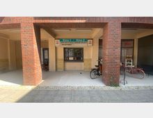 Eingangsbereich eines kleinen Kinos mit zwei Säulen aus rotem Backstein. Über dem Eingang hängen Schilder mit den Beschriftungen „Kino 1“ und „Kino 2“, Fahrräder stehen daneben, und im Hintergrund ist ein Schaufenster zu sehen.