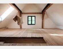 Minimalistischer Dachboden mit Holzboden, sichtbaren Holzbalken und einem kleinen schwarzen Fenster in der weißen Wand. Tageslicht strömt durch ein Dachfenster ein, und Kleidung hängt an einer Schnur quer durch den Raum.