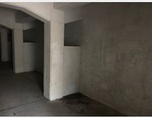 Dunkler, leerer Raum mit rohen Betonwänden, stützenden Betonpfeilern und einer schlichten, unfertigen Struktur. Der Boden besteht aus glattem Beton, und die Umgebung wirkt industriell oder unfertig.