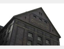 Backsteingebäude mit einem Giebeldach, auf dem das Wort "Westhafen" eingraviert ist. Die Fassade besitzt rechteckige Fenster mit Sprossen und eingefasste dekorative Elemente.