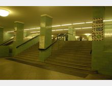 U-Bahn-Station mit einer Treppe, Fliesen in hellgrüner Farbe und richtungsweisenden Schildern für die Linien U5, U8 und S-Bahn. Die Beleuchtung erfolgt durch große Deckenlampen, und Rolltreppen befinden sich neben der Treppe.