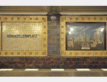 Station „Hohenzollernplatz“ in einer Berliner U-Bahn-Station mit beige gefliester Wand, Schriftzug „Hohenzollernplatz“ auf Keramikfliesen und einem Bild, das historische Gebäude mit Türmen zeigt. Die Wand ist durch Zierelemente und dunkle Sockelfliesen detailliert gestaltet.