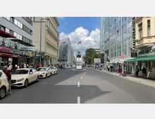 Straßenszene am Checkpoint Charlie in Berlin mit einer kleinen Wachhütte in der Mitte der Straße, flankiert von historischen und modernen Gebäuden. Im Hintergrund ist die US-amerikanische Flagge und ein großes Foto eines Soldaten zu sehen, umgeben von Geschäften, Restaurants und Besuchern.