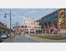 Straßenansicht des Einkaufszentrums "Alexa" in Berlin mit markanter rosafarbener Fassade, großen Glasfenstern und einem auffälligen Schriftzug auf dem Dach. Rechts an der Fassade ist ein großflächiges Kunstwerk angebracht, während links eine Bahnstrecke mit gemauerten Bögen verläuft.