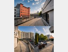 Erhöhte Dachterrasse bzw. umlaufender Gehweg mit Kieselboden und Metallgeländern zwischen mehrstöckigen Gebäuden, mit Blick auf eine rote Backsteinfassade und umliegende Stadtbebauung. Ein Bereich der Terrasse ist mit Lounge-Möbeln, Pflanzkübeln und einem Sonnensegel ausgestattet.