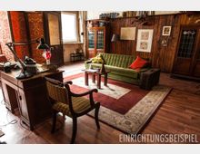 Gemütlich eingerichteter Raum mit Holzwänden, einem grünen Sofa, einem Holztisch und Retro-Möbeln. Ein orientalischer Teppich bedeckt den Holzboden, Bücherregale und dekorative Details ergänzen die Einrichtung.