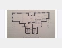 Grundriss eines Wohnbereichs, bestehend aus mehreren Zimmern, einer Küche, zwei Badezimmern, Fluren und einem Balkon. Maßangaben und Türen sind eingezeichnet, zentral befindet sich ein Treppenhaus.