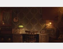 Ein rustikaler Arbeitsplatz in einem Raum mit dunkel gemusterten Tapeten. Zu sehen sind ein Holztisch mit Schubladen, ein Holzstuhl, eine grüne Tischlampe, eine Wanddekoration mit einer Laute und ein gerahmter Spiegel sowie eine indirekte Beleuchtung.