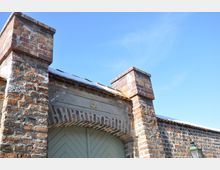 Historisches Gebäude mit einer Backsteinfassade und einem Torbogen, über dem ein Davidstern angebracht ist. Im Hintergrund ist ein klarer blauer Himmel zu sehen.