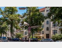 Straßenecke mit Straßenschildern "Taunusstraße" und "Görresstraße" vor einem mehrstöckigen Wohnhaus mit hellbeiger Fassade und Rundbogenfenstern, umgeben von Bäumen und parkenden Autos.