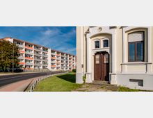 Eine Straßenszene mit einem modernen mehrstöckigen Wohngebäude mit weißen Fassaden und orangefarbenen Balkonen im Hintergrund. Im Vordergrund ist ein älteres Gebäude mit hellgelber Fassade, brauner Eingangstür und großen Fenstern zu sehen; daneben verläuft eine asphaltierte Straße mit Gehweg und Grünfläche.