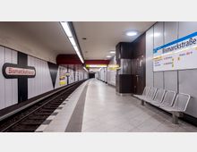 U-Bahn-Station mit moderner Gestaltung, benannt "Bismarckstraße". Die Wände sind mit schwarzen und weißen Paneelen gestaltet, Gleise verlaufen durch die Station, und an der rechten Seite befinden sich Metallbänke sowie ein Wegweiser mit Linien- und Richtungsinformationen.