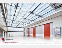 Moderner Konferenzraum mit hellem, offenen Design. Sichtbar sind eine deckenhohe Glasdecke mit Metallstreben, rot-graue Trennwände, eine Galerie mit Geländer und weiße Wände.