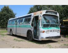 Ein alter Bus mit grün-weißer Lackierung, der am Rand eines offenen Geländes steht. Der Bus hat runde Scheinwerfer, große Seitenfenster und trägt die Nummer "4506" sowie die Aufschrift "Special Service".