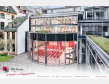 Außenansicht des dbb forums Berlin, einem modernen Kongress- und Tagungszentrum mit einer gläsernen Fassade und abgerundeten Panoramafenstern. Im Inneren sind rote Stuhlreihen und Veranstaltungsräume sichtbar, umgeben von umliegenden Gebäuden mit traditionellen Elementen und begrüntem Dach.