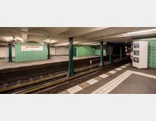 U-Bahn-Station mit grünen Kacheln und Beschilderung "Wittenbergplatz" für die Linie U2. Die Station hat mittige Bahnsteige, gekachelte Wände, Metallstützen und Gleise mit Sicht auf Sicherheitsmonitore auf der rechten Seite.