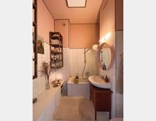 Kleines Badezimmer mit weißen Fliesen und rosa gestrichenen Wänden. Es gibt eine Badewanne mit Duschkopf, ein weißes Waschbecken auf einem Holzunterschrank, ein rundes beleuchtetes Spiegel, sowie ein Holzregal mit Handtüchern und Dekorationen.