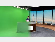 Ein Studio mit einer grünen Wand (Green Screen) und einem hölzernen Pult, das teilweise durch den Hintergrund-Effekt transparent erscheint. Im rechten Bereich des Bildes ist eine Fensterfront mit Blick auf eine Stadtlandschaft, einschließlich eines Fernsehturms bei Sonnenuntergang, zu sehen.