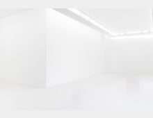 Weißer, minimalistischer Innenraum mit glatten Wänden, einer Ecke und einer Deckenbeleuchtung, die in einer Einfassung angebracht ist. Der Boden ist ebenfalls weiß und reflektierend.