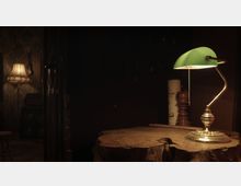 Ein dunkler Raum mit einem rustikalen Holztisch im Vordergrund, auf dem eine klassische Tischlampe mit grünem Lampenschirm steht. Im Hintergrund sind eine Stehlampe mit Stoffschirm, eine an der Wand hängende Ukulele und leicht erkennbare Holz- und Dekorelemente zu sehen.