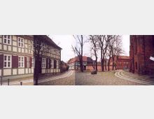 Panoramaansicht eines historischen Hofes mit Fachwerkhäusern und einer Kirche aus rotem Backstein. Der Hof ist mit Kopfsteinpflaster bedeckt, umgeben von kahlen Bäumen und begrenzt durch eine Mauer.