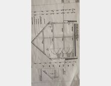 Bauplan eines mehrgeschossigen Gebäudes mit vertikalem Schnitt. Sichtbar sind Treppenverläufe, Räume wie Büro, Küche und Heizungsraum sowie Maße und technische Details der Konstruktion einschließlich Dach- und Fassadenaufbau.