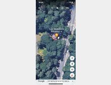 Luftaufnahme eines Biergartens ("Cafe Rodelhütte") umgeben von dichtem Wald an der Onkel-Tom-Straße. Ein kleiner Parkplatz und ein Fußgängerüberweg sind in der Nähe sichtbar.