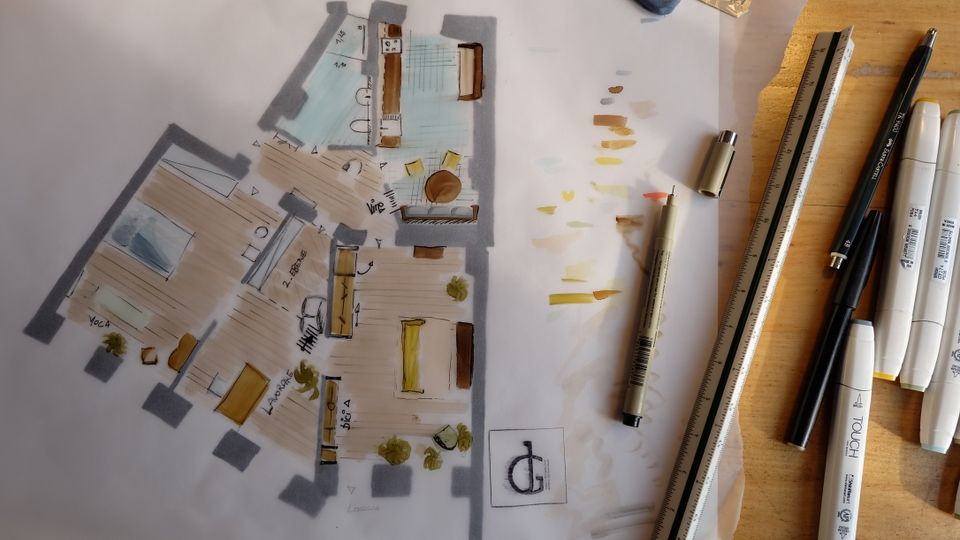 Handgezeichneter Grundriss einer Wohnung auf Transparentpapier mit farbigen Markierungen für Räume und Möbel. Daneben liegen Zeichenwerkzeuge wie Lineal, Stifte und Marker auf einer Holzarbeitsfläche.