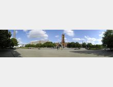 Weitläufiger Platz mit gepflastertem Boden, Brunnen in der Mitte und der roten Backsteinfassade des Berliner Rathauses im Hintergrund; umgeben von Bäumen und modernen Gebäuden, mit dem Fernsehturm am linken Bildrand erkennbar.