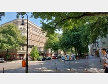 Kreuzung einer ruhigen Stadtstraße mit gepflastertem Boden, umgeben von Bäumen und historischen Wohnhäusern mit hellen Fassaden. Straßenschilder weisen auf die Reichenberger Straße und die Liegnitzer Straße hin, neben geparkten Autos und vereinzelten Passanten.