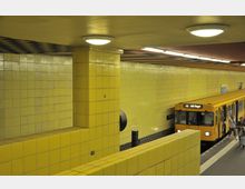 Gelb gefliester U-Bahnsteig mit einer stehenden gelben U-Bahn der Linie U6 in Richtung Alt-Tegel. Menschen betreten den Bahnsteig, und die Wände sowie Säulen sind durchgehend in gelbe Fliesen gekachelt.