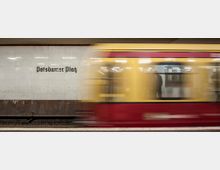 Ein Bahnsteig der S-Bahn-Station "Potsdamer Platz" in Berlin, mit einer vorbeifahrenden gelb-roten S-Bahn im Vordergrund und einer gefliesten Wand mit der Stationsaufschrift im Hintergrund.