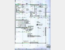 Grundriss eines Wohnhauses mit detaillierter Raumaufteilung und Bemaßungen. Die Zeichnung zeigt verschiedene Räume wie Küche, Wohnzimmer, WC und Treppenbereich mit Angaben zu Flächenmaßen und Baumaterialien, ergänzt durch technische Details wie Wand- und Fußbodenaufbauten.