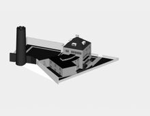 Eine schematische Darstellung eines Gebäudekomplexes mit einem mehrstöckigen Hauptgebäude, Flachdächern und mehreren angrenzenden Strukturen. Links im Bild befindet sich ein runder schwarzer Turm, der an den Gebäudekomplex angeschlossen ist, umgeben von einer rechteckigen Einfriedung.