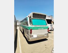 Ein historischer Bus mit grüner und silberner Lackierung, beschriftet mit "Culver City Municipal Bus Lines" und der Nummer "4506", steht auf einem Parkplatz bei sonnigem Wetter. Im Hintergrund sind andere Fahrzeuge, darunter ein weiteres größeres Fahrzeug, sichtbar.