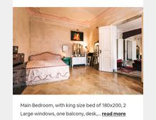 Geräumiges Schlafzimmer mit einem großen Bett, antiken Möbeln, einem Schminktisch und Holzboden. Die Wände sind leicht abgenutzt, und es gibt Stuckverzierungen an der Zimmerdecke sowie Doppeltüren, die zu einem angrenzenden Raum führen.