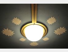 Runde Deckenleuchte mit goldenem Rahmen und einer milchigen Glaskuppel, umgeben von dekorativen sternförmigen Mustern auf einer blaugrauen Decke.